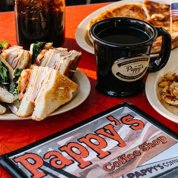 A table at Pappy's Coffee Shop with a club sandwich, coffee, and breakfast plate.